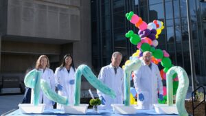 Photo of four scientists in white coats in front of a laboratory display outside