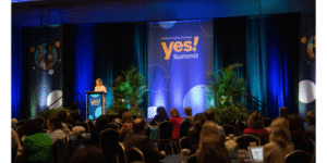 photo of a speaker presenting to a crowded room at the YES! Summit