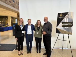Photo of four individuals standing in a group, facing the camera.