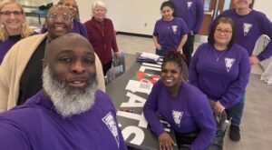 A group of individuals take a selfie around a table