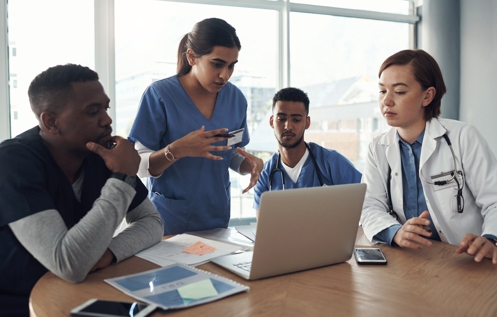 Group of four medical professionals surrounding a laptop